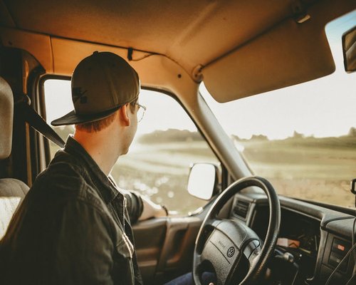 man driving a car looking relaxed on a sunny day